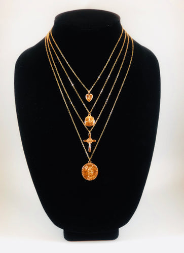 Set of four gold necklaces that can be layered or worn separately. Set includes Heart Charm with Rhinestone North Star Necklace, Compass Charm Necklace, Cross Charm Necklace, and Coin Charm Necklace.  Approximately 16-18-20-22
